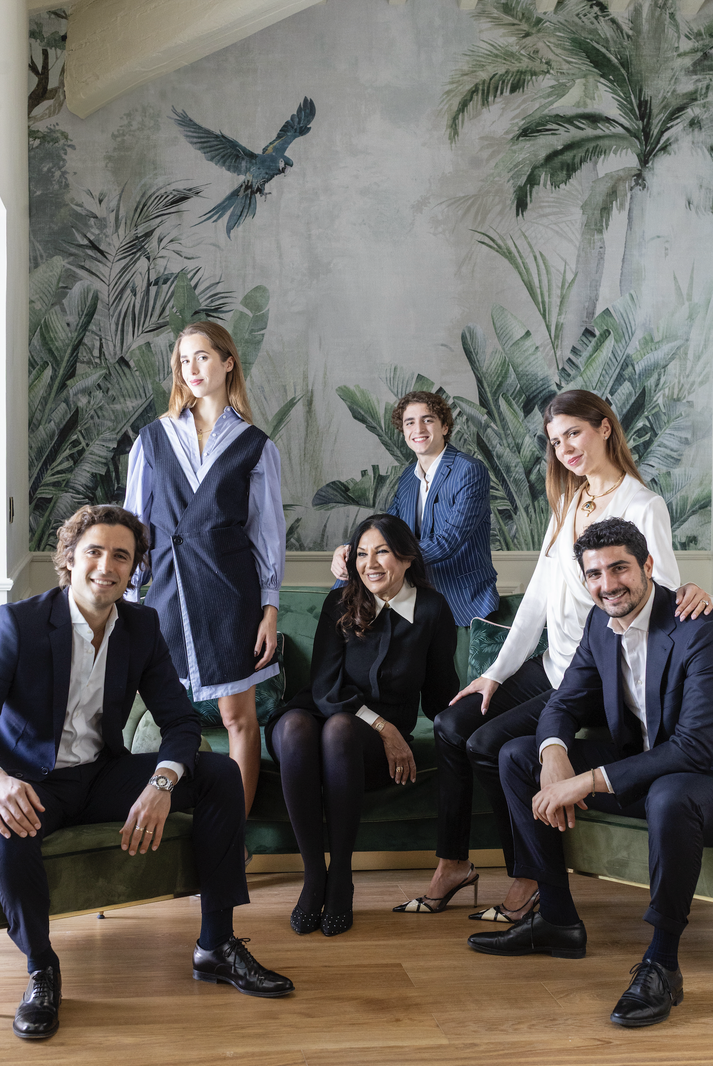 The La Gemma family seated together in front of the hotel's tropical mural