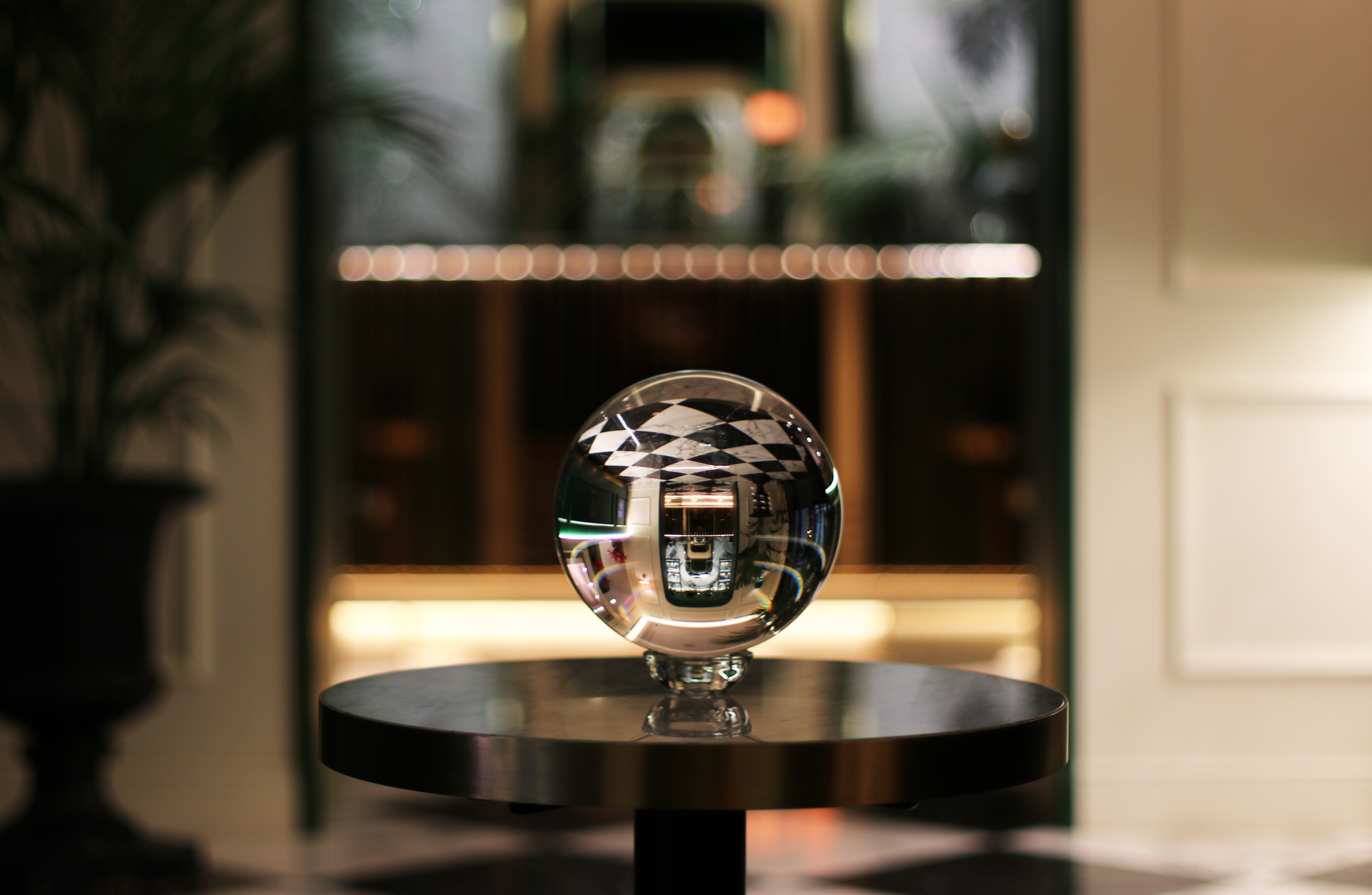 A crystal glass sphere on a pedestal table reflecting La Gemma's warmly lit Florentine interior